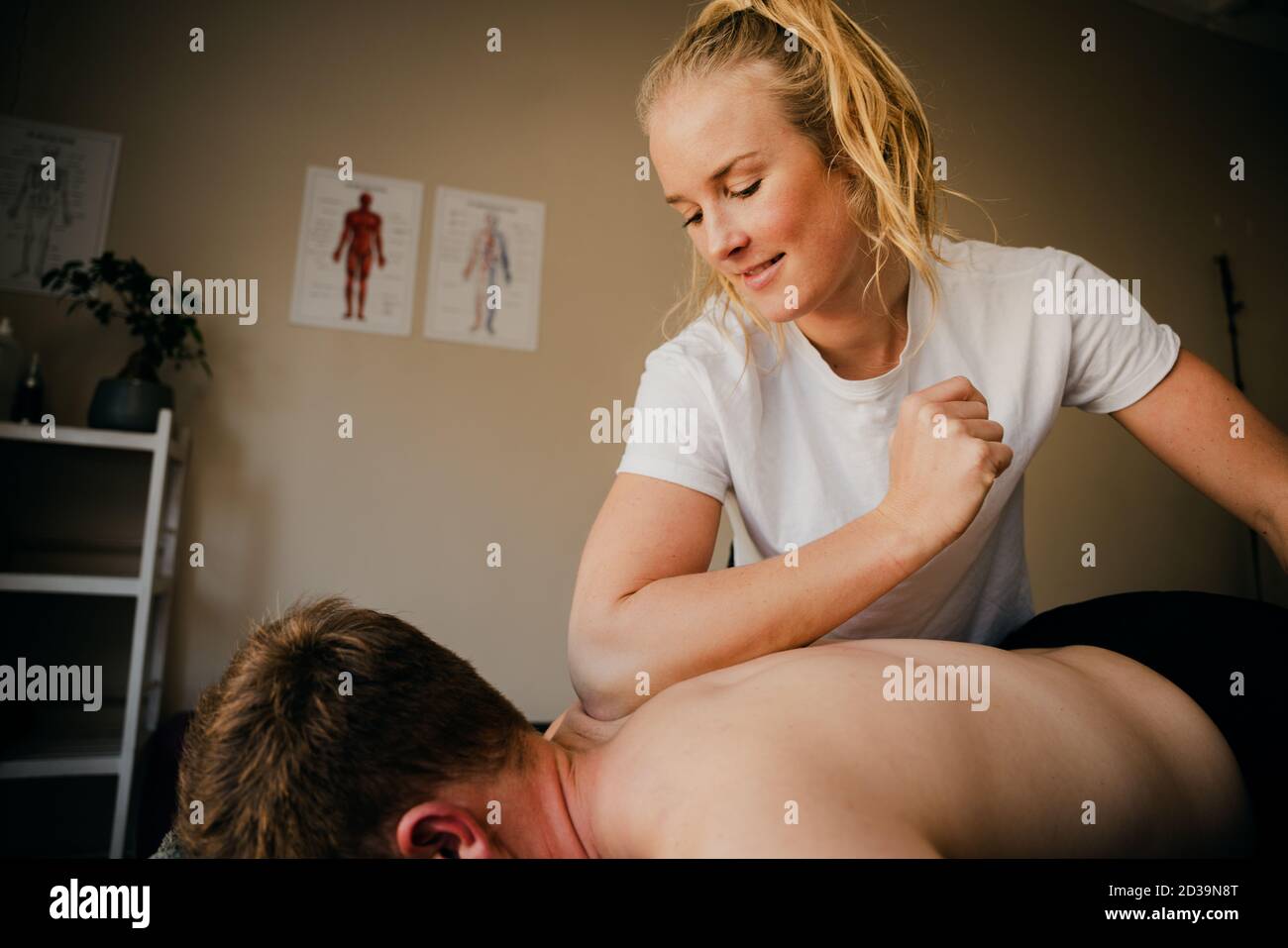 Young attractive woman osteopath doing back massage. Blonde on a
