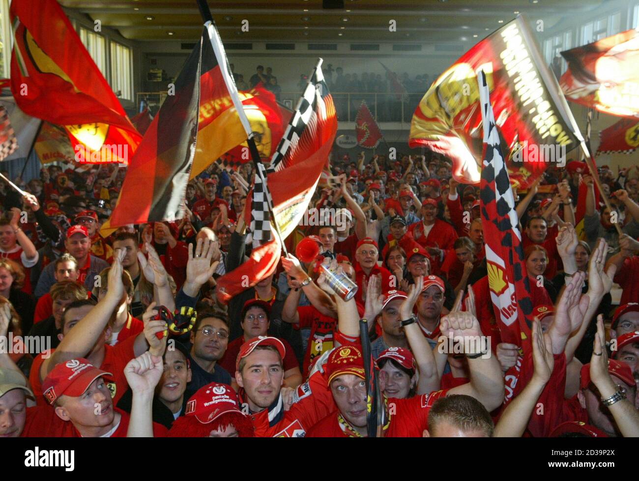 Supporters of German Formula One driver Michael Schumacher and the Ferrari team wave flags while watching the season-ending Formula One Japanese Grand Prix race in Suzuka, central Japan, on a large viedeo screen in Schumacher's western German hometown of Kerpen near Cologne October 12, 2003. Schumacher won the World Championships title a record sixth time after placing 8th in Suzuka. REUTERS/Wolfgang Rattay  WR/AA Stock Photo