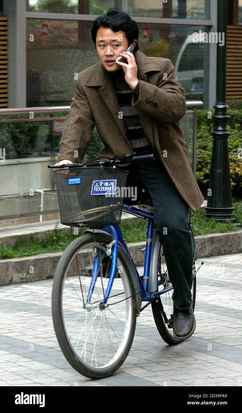 A cyclist talks on his mobile phone in Shanghai December 3, 2003. The officially Communist country, which once discouraged private citizens from owning luxury items such as telephones, hit a milestone last weekend when it became one of the few markets to boast more mobile phone subscribers than fixed-line users. Stock Photo