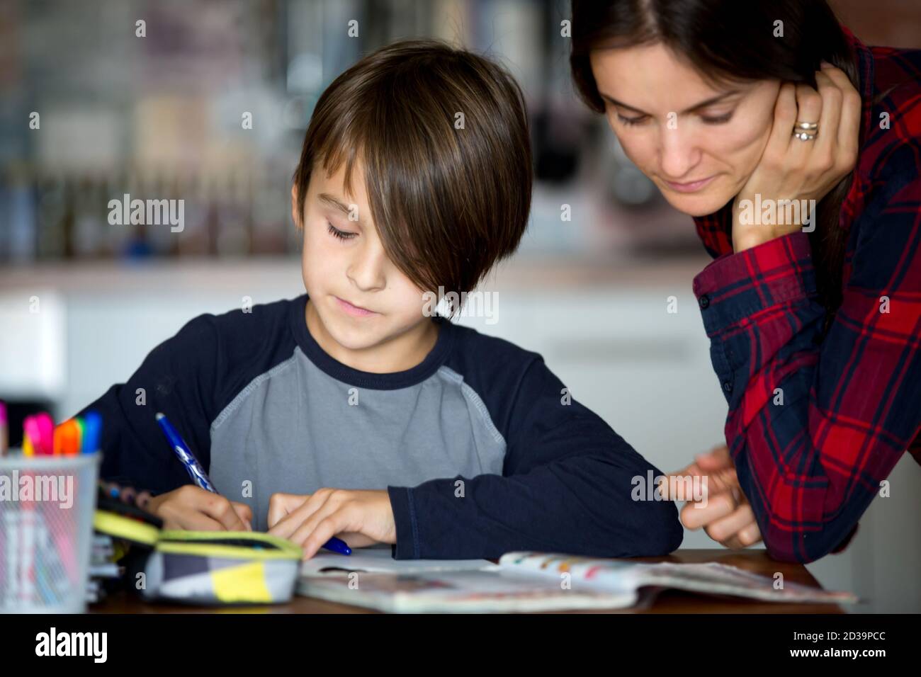 Mother, helping her child with homeworks, kid learning at home during ...