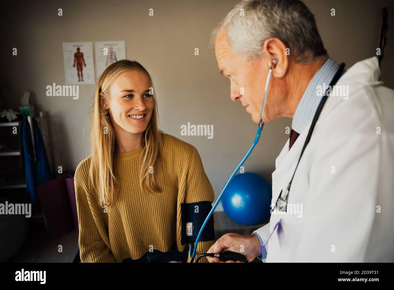 Young female patient smiling while blood pressure is tested by elderly