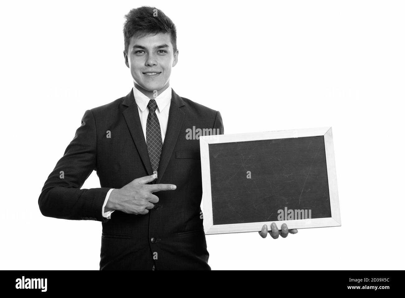 Young happy businessman smiling while holding blank blackboard and pointing finger Stock Photo