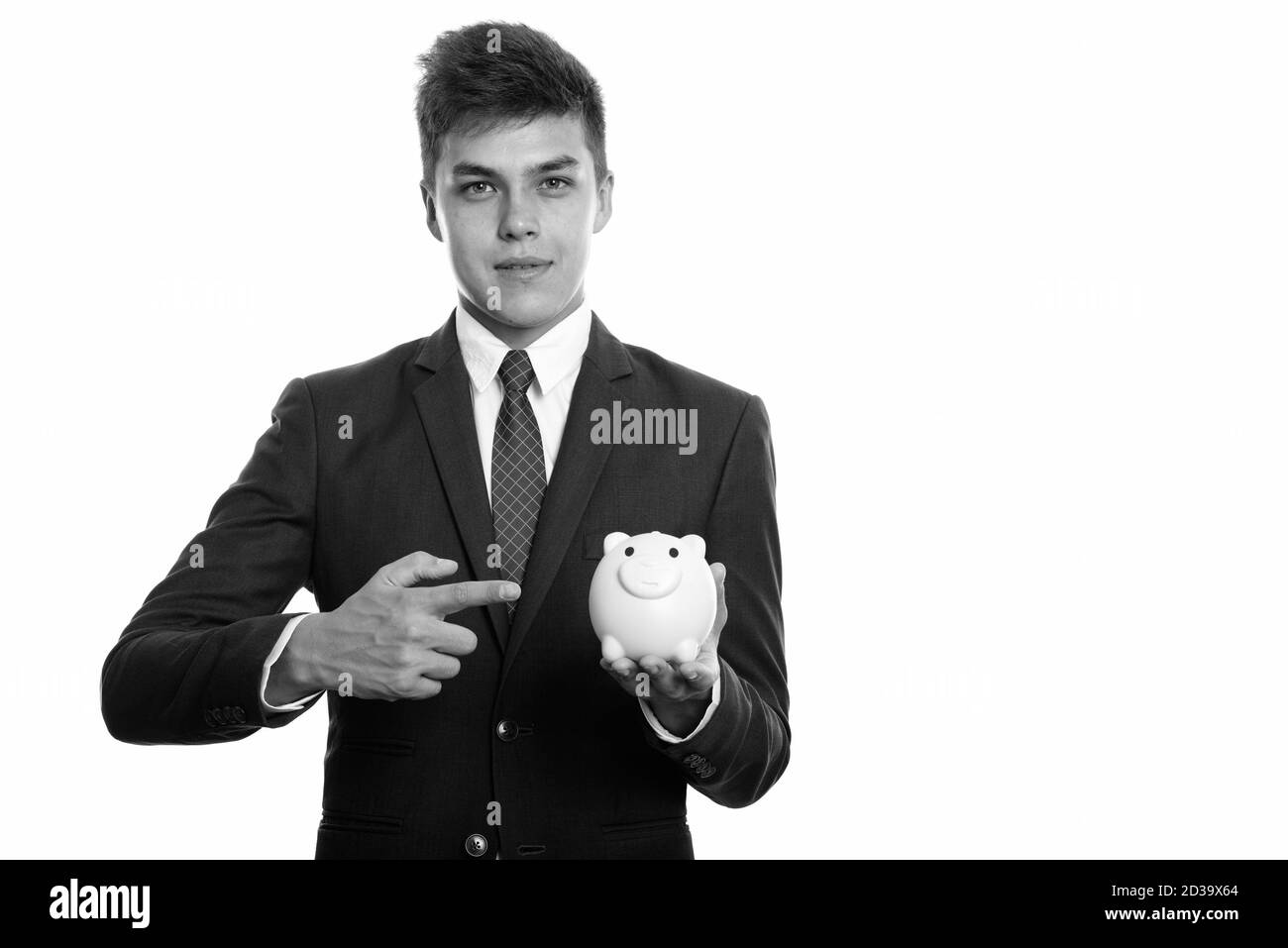 Young handsome businessman holding piggy bank and pointing finger Stock Photo