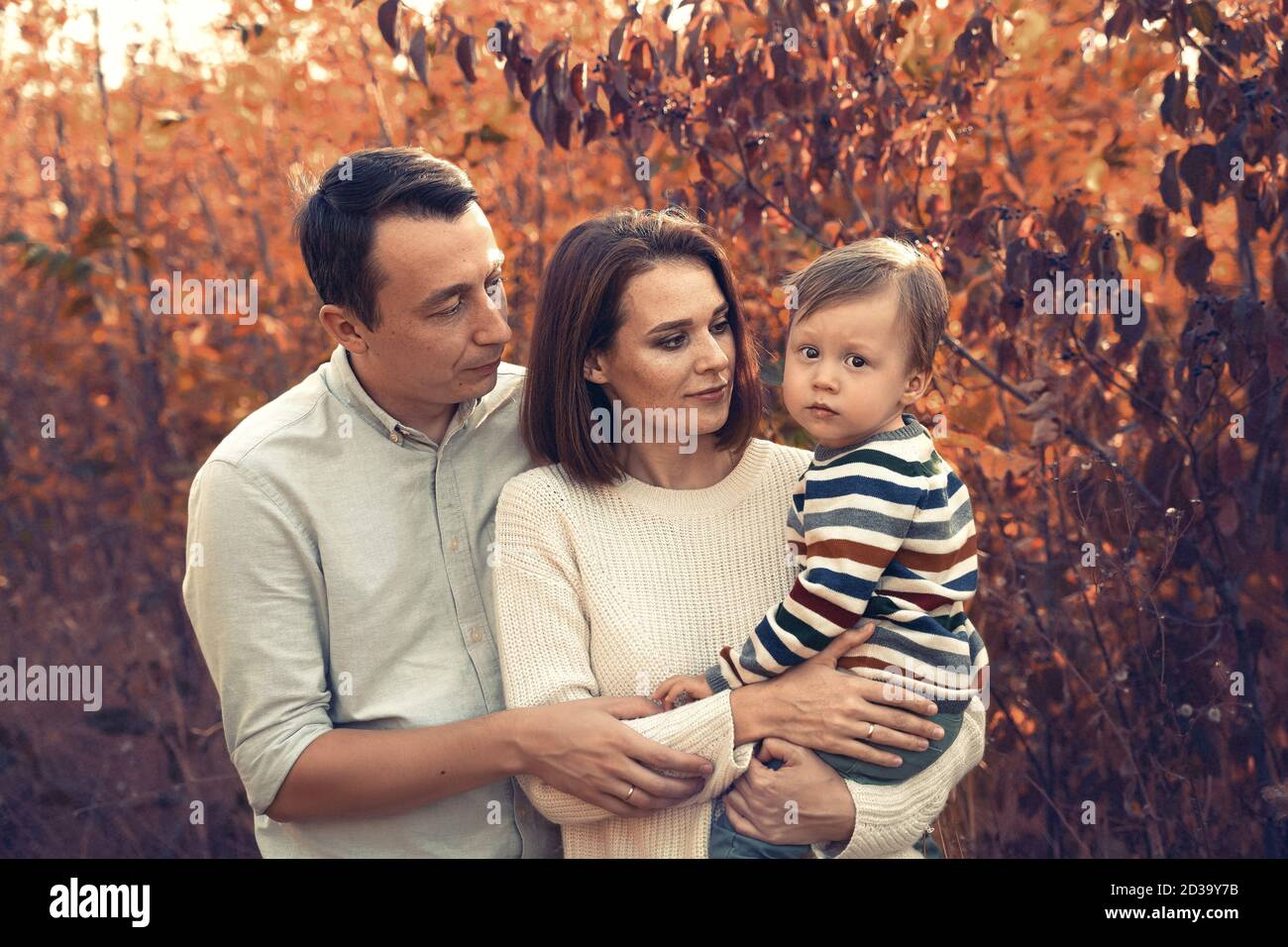 Beautiful young family with a small child on an autumn walk. Stock Photo