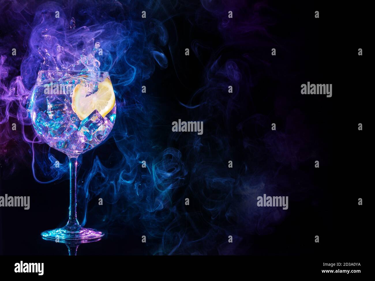 gin tonic cocktail splashing in blue and purple smoky background Stock Photo
