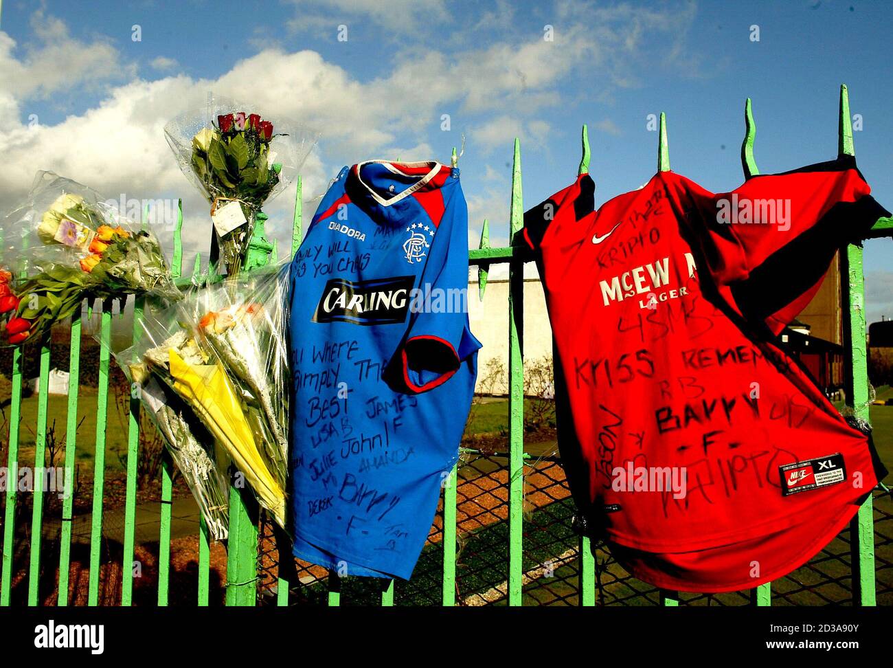 Flowers and Rangers' football shirts hang from a fence in Kenmure Street, Glasgow, where 15-year-old murder victim Kriss Donald was snatched by a group of men near his home, March 17, 2004. Donald was snatched on Monday by five men said by police to be of Asian appearance, in southern Glasgow and his badly beaten body was found the next day behind a Celtic supporters' club in the east end of the city. REUTERS/Jeff J Mitchell  JJM/MD/THI Stock Photo