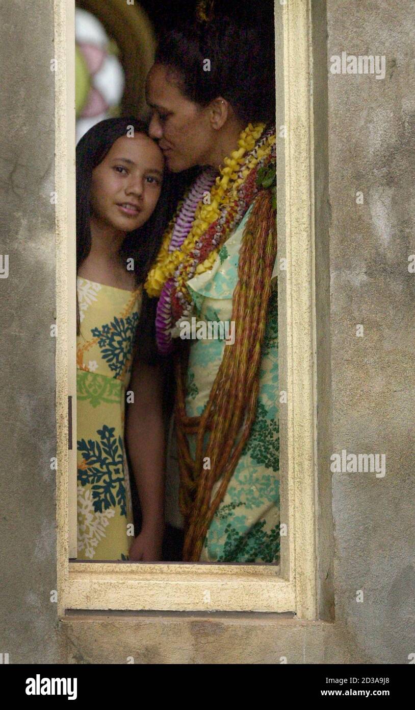 Hoakalei Hina Kamauu gives her daughter Iolani, 11, a kiss while standing in a chapel (which was the former mausoleum) on the grounds of the Royal Mausoleum or Mauna Ala (Fragrant Mountain) in Honolulu, Hawaii, May 2, 2004. Kamauu, the queen of Hawaii's Lei Day ceremony, took a break after a 77-year old annual ritual consisting of offering elaborate leis from the prior day's Lei Day festivities and placing the intricate, hand-made flowered necklaces on the tombs of famous Hawaiian monarchs. Picture taken May 2, 2004. REUTERS/Lucy Pemoni  LP/HB Stock Photo