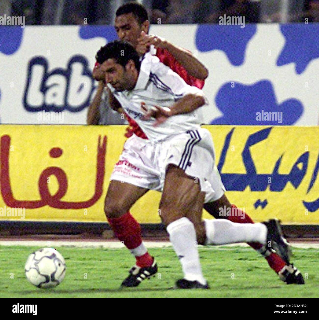 Real Madrid soccer player Luis figo (front) slips away from Egyptian  al-Ahli defender Abu-Maged Mostafa during a friendly match in Cairo August  4, 2001. Both soccer teams Real Madrid and al-Ahli were