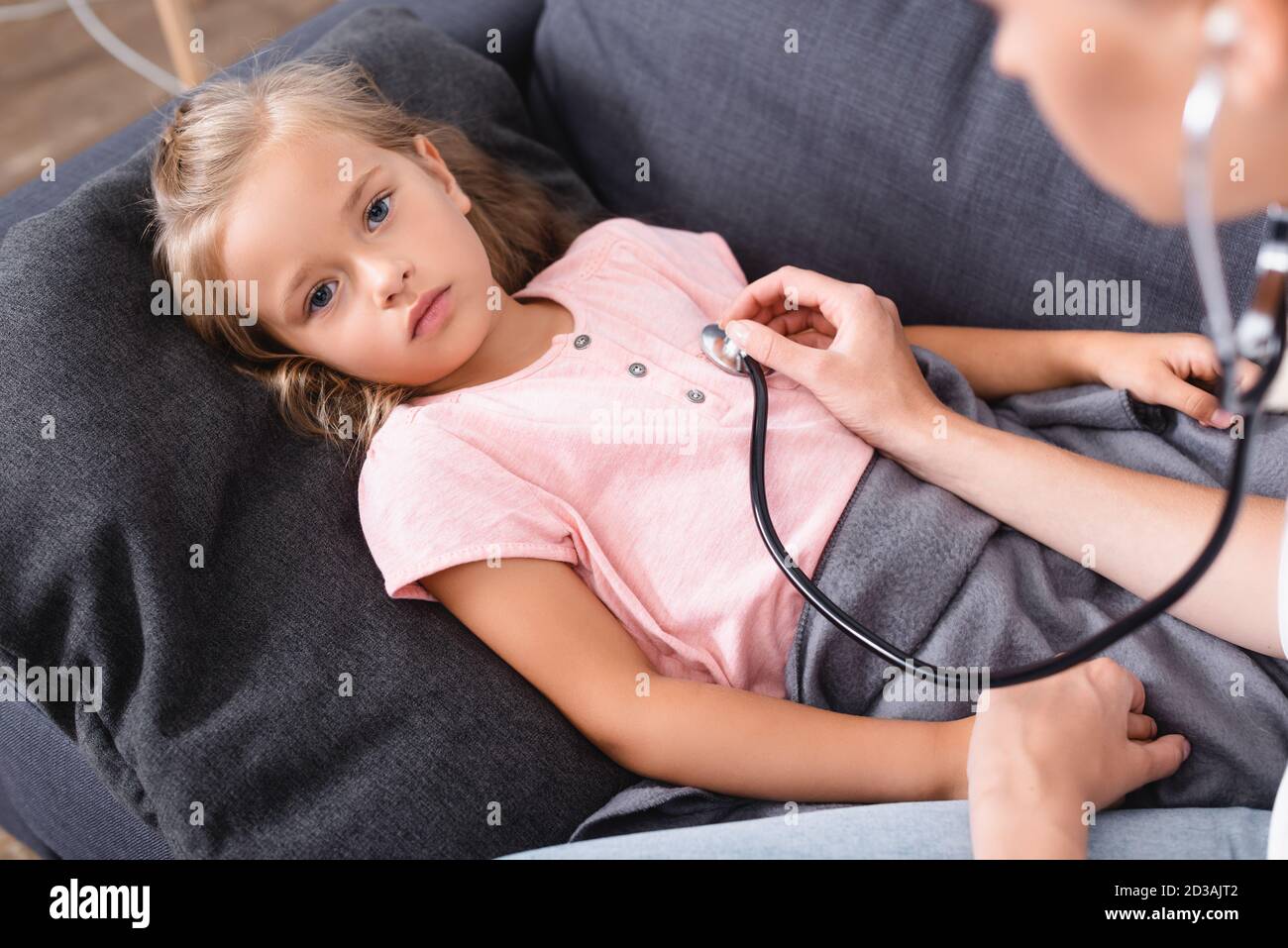 Selective focus of ill child holding hand of mother in stethoscope Stock Photo