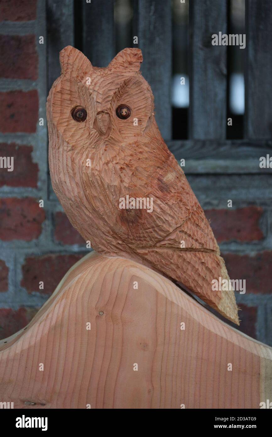 Carved owl sits on top of a chaircarved from a tree trunk Stock Photo