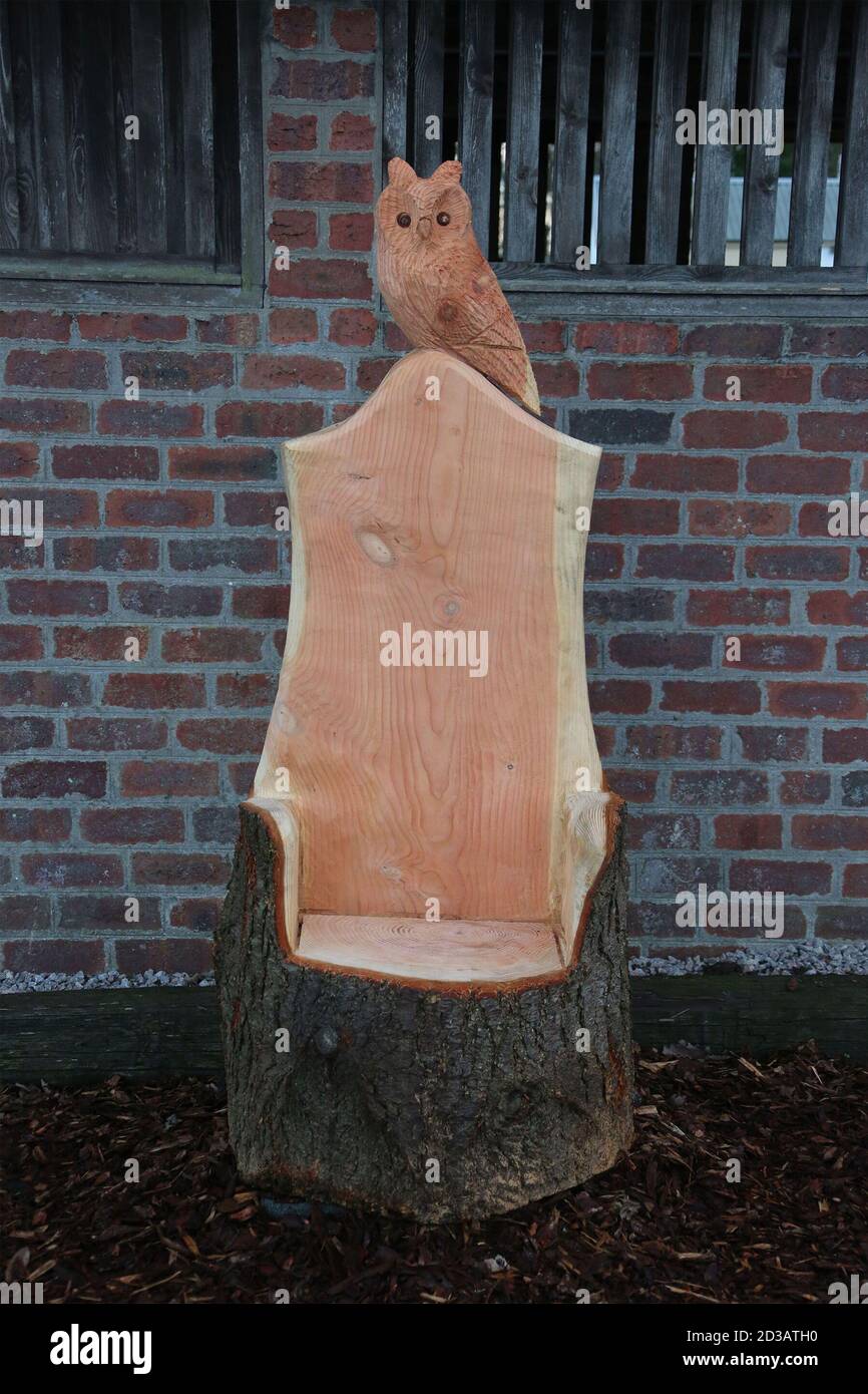 Carved owl sits on top of a chaircarved from a tree trunk Stock Photo