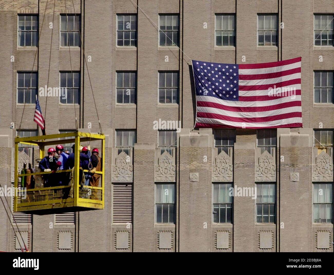 A Group Of Workers In A Basket Suspended From A Crane Are Transported Past A Flag Draped Building At The Site Of The World Trade Center Attacks September 26 01 In New York A Group Of Workers In A Basket Suspended From A Crane Are Transported Past A Flag Draped Building At The Site Of The World Trade Center Attacks September 26 01 In New York