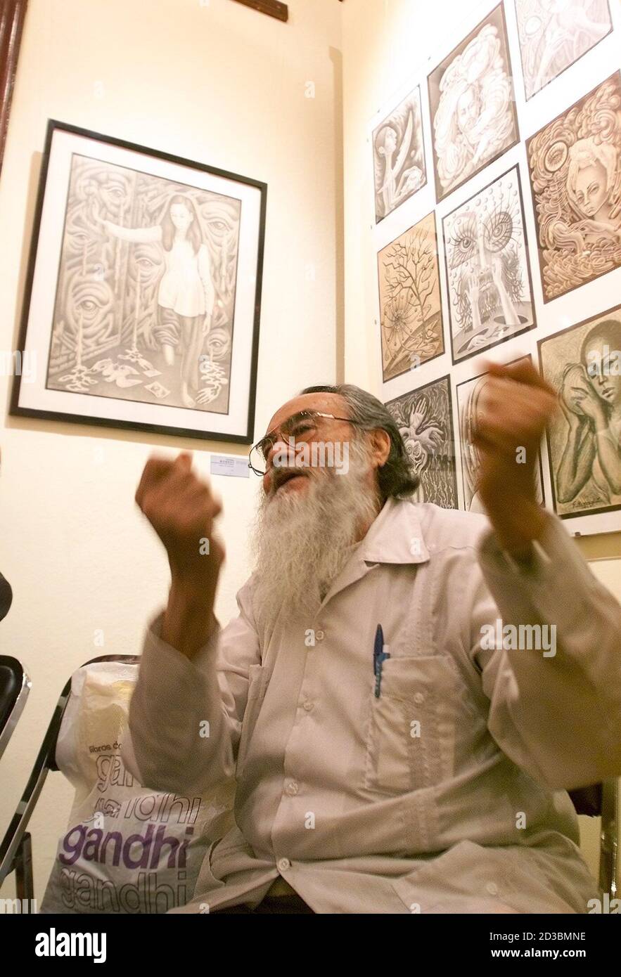 Guillermo Monroy, a student of Mexican cult artist Frida Kahlo, gestures as he chats in front of his paintings at a joint exhibition of work by former students of Kahlo in Mexico City, November 12, 2002. A small group of painters known as the 'Fridos' studied under Mexican painter Frida Kahlo and still pay homage to her in their art. Interest in the life and art of Frida Kahlo has been rekindled by the Hollywood film 'Frida' based on her life staring Mexican actress Salma Hayek. REUTERS/Daniel Aguilar/FOR FEATURE ARTS-KAHLO  AW/ME Stock Photo