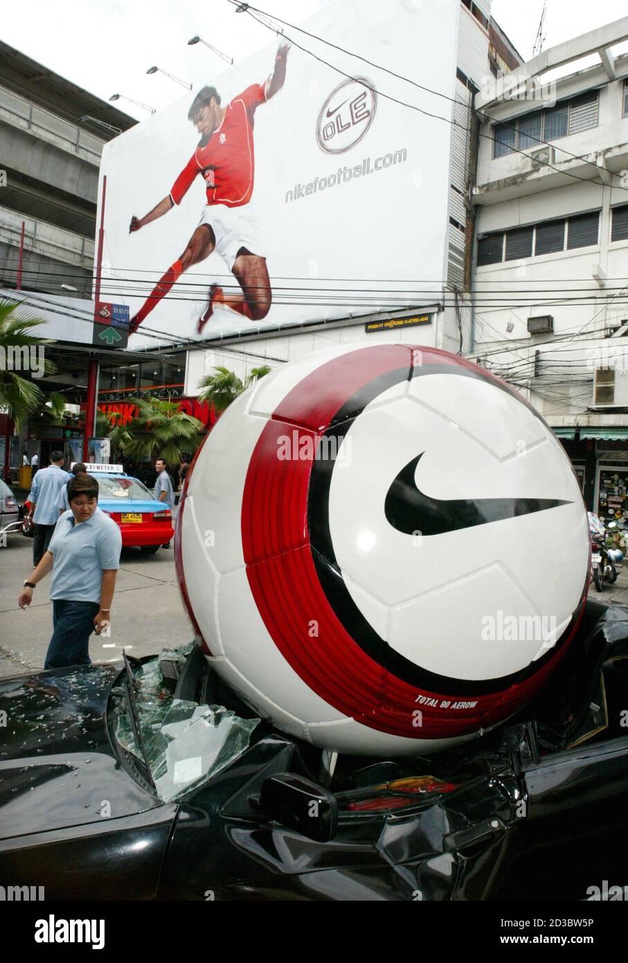 A Thai bypasser looks at a giant football sitting on top of a car in  Bangkok on May 31, 2004. The exhibit was part of a promotion for the Euro  2004 soccer