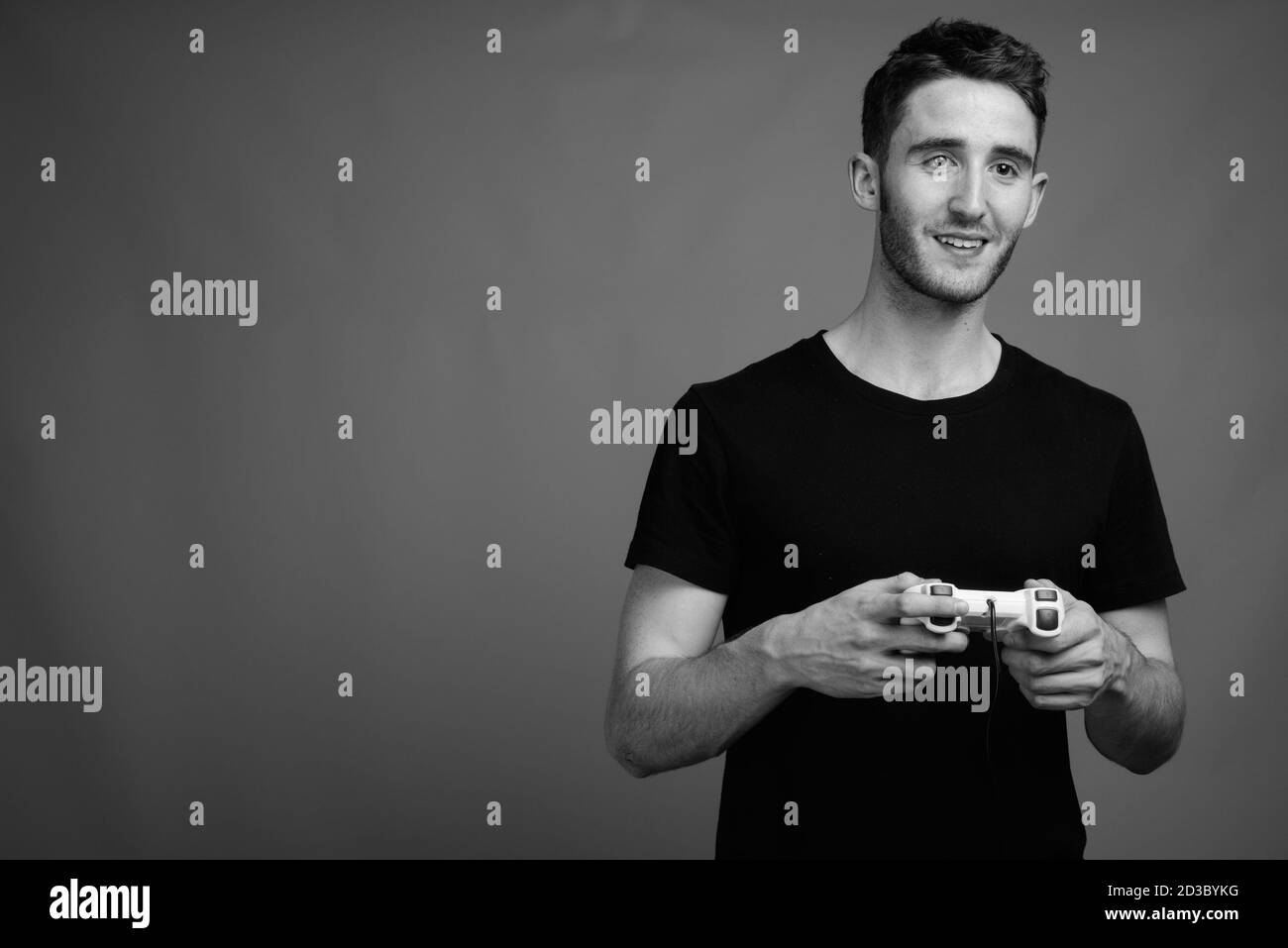 Young handsome man playing games against gray background Stock Photo