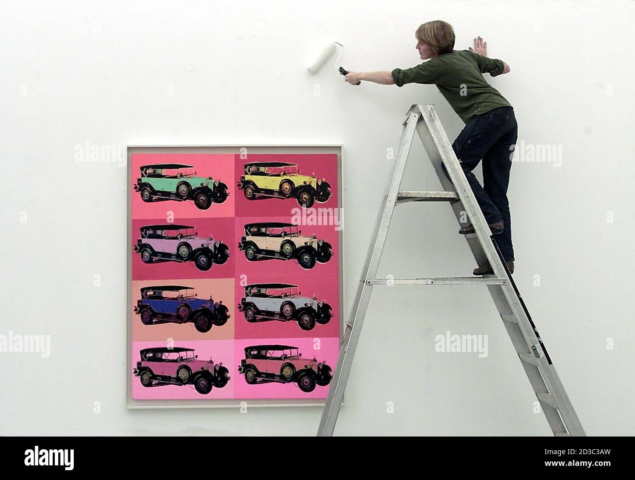 A gallery assistant white washes the walls around the Andy Warhol Painting 'Mercedes Type 400 Touring Car', an acrylic and silk screen ink on canvas, in the Milton Keynes Gallery, September 7, 2001. The works all belong to the Car series, Warhol's last cycle of paintings before his death in 1987. It is their first showing in Britain. REUTERS/Darren Staples  DS/MC/AA Stock Photo