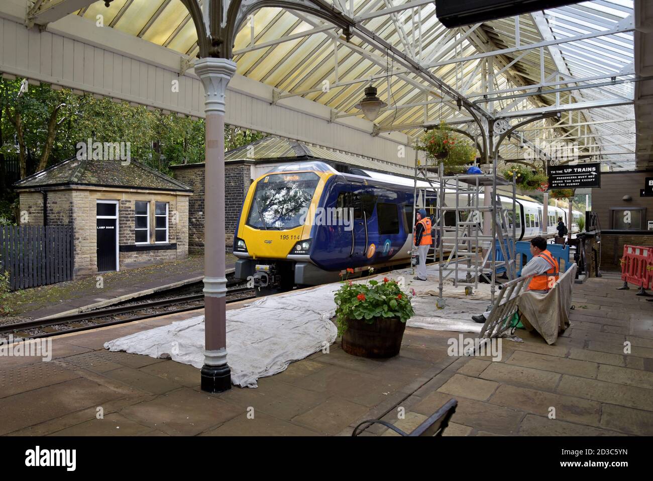 Painters and decorators working on the platform as a Class 196 train arrives at Hebden Bridge Railway Station, Yorkshire, UK Stock Photo