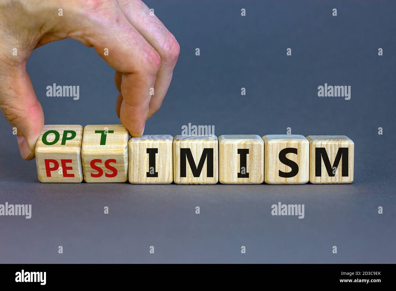 Male hand turns cubes and changes the expression 'pessimism' to 'optimism'. Beautiful grey background. Business concept. Copy space. Stock Photo