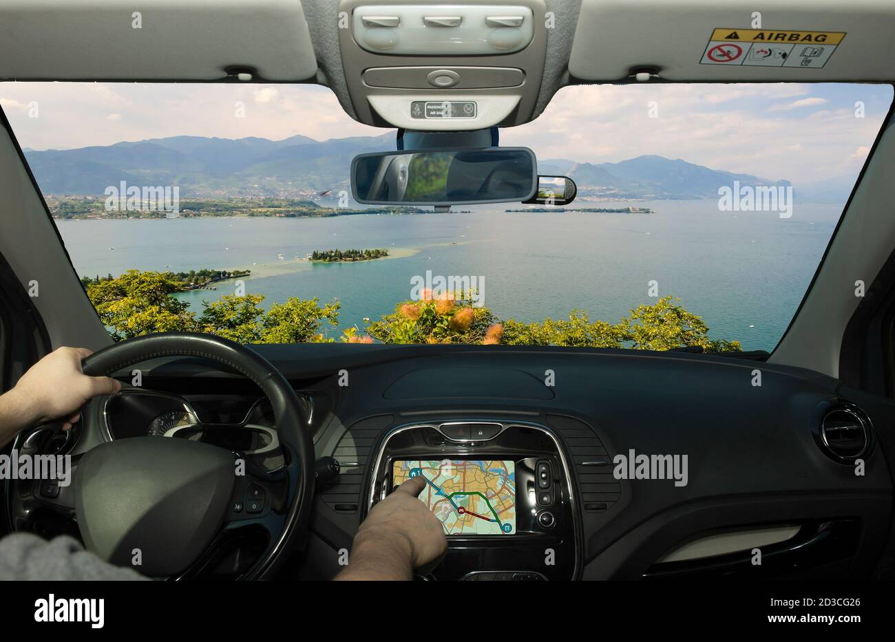 Driving a car while using the touch screen of a GPS navigation system towards Lake Garda, Italy Stock Photo