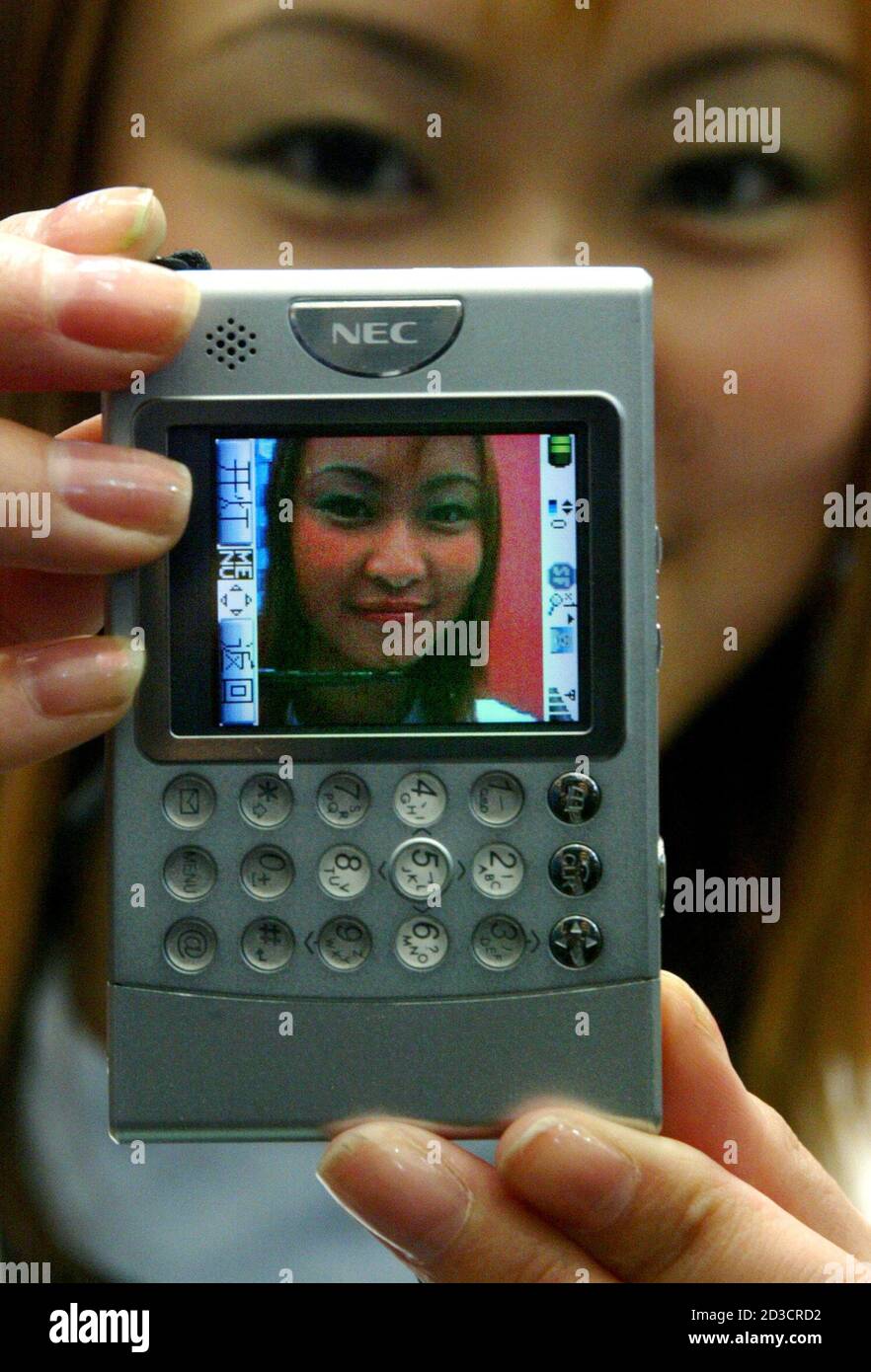 A Chinese promoter shows a new NEC-N900 mobile phone camera at CeBit Asia  2004 information technology fair in Shanghai April 27, 2004. The phone's  height is 85 mm and width 54 mm,