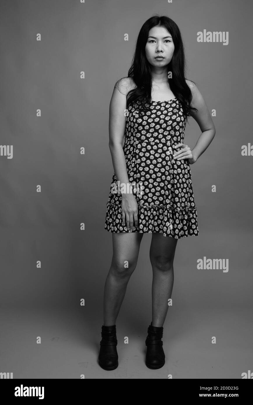 Asian woman wearing dress against gray background Stock Photo