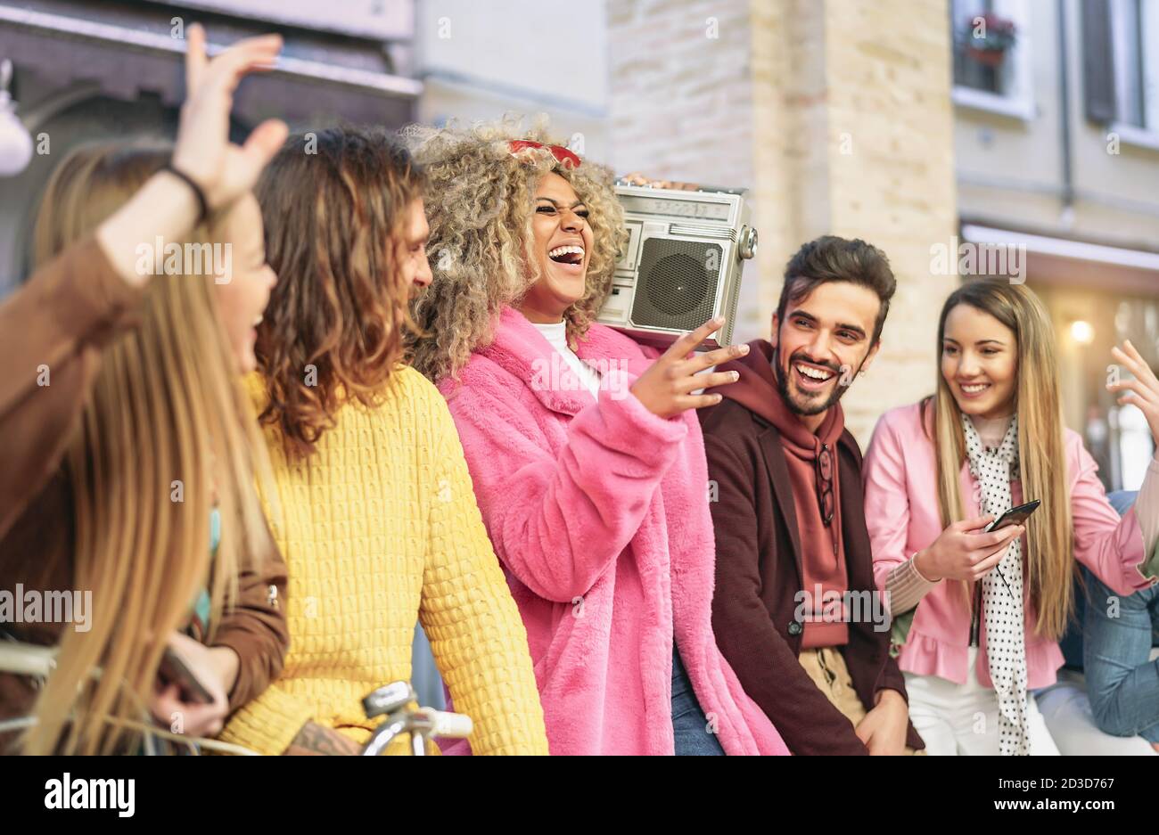Group friends having fun listening music with vintage boombox - Happy young people making party in city outdoor Stock Photo