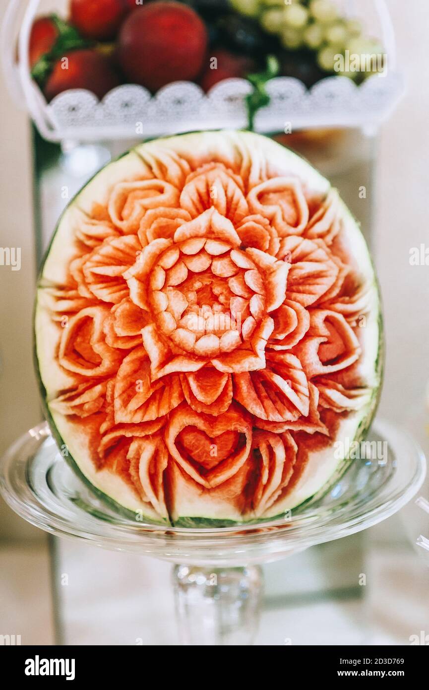 Watermelon carving art. Carved beautiful flower on a large watermelon to serve on a sweet table. Concept of carving fruit and vegetable compositions. Stock Photo