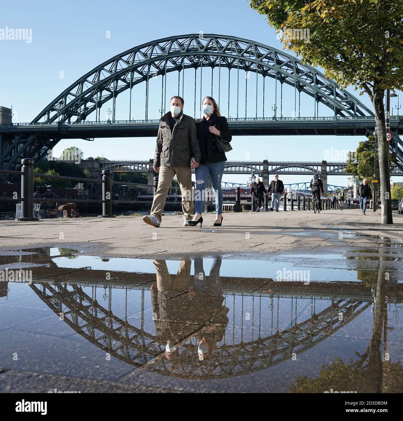 People wearing masks walking near the Tyne Bridge in Newcastle. Ministers are considering imposing fresh regional restrictions amid a spike in coronavirus cases in northern England. Stock Photo