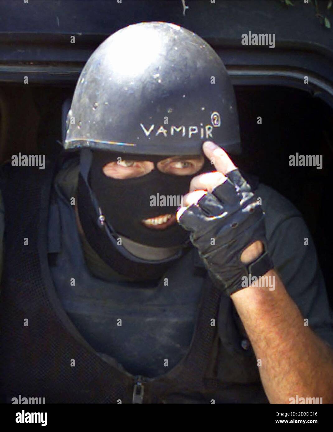 A Masked Macedonian Soldier Points To His Helmet With The Word Vampire Written On It As His Unit Patrols In The Village Of Aracinovo June 27 2001 Macedonian Police Conducted A House