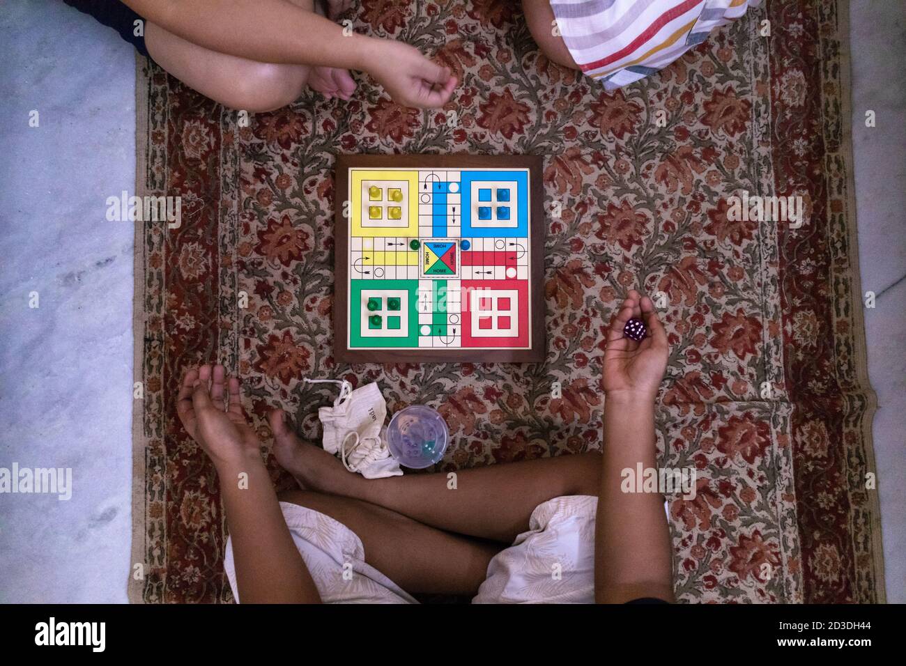 Children and adults play ludo game at home during holidays in India. Oct 2020 Stock Photo