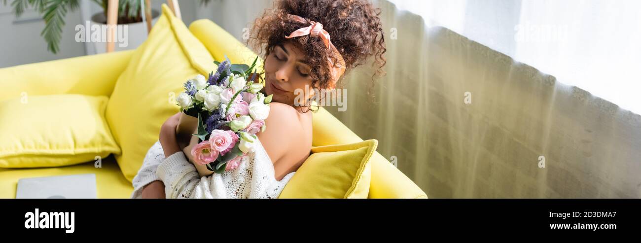 horizontal image of young woman with closed eyes holding bouquet and ...