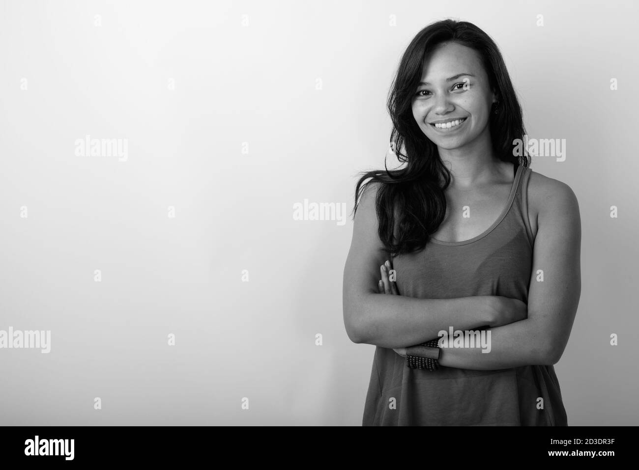 Studio shot of young happy Asian woman smiling with arms crossed ...