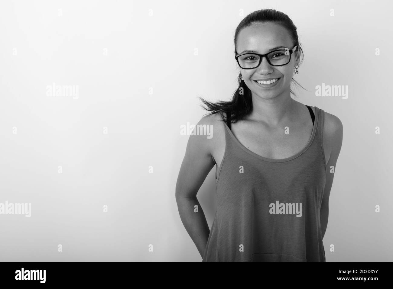 Studio shot of young happy Asian woman smiling while wearing eyeglasses ...