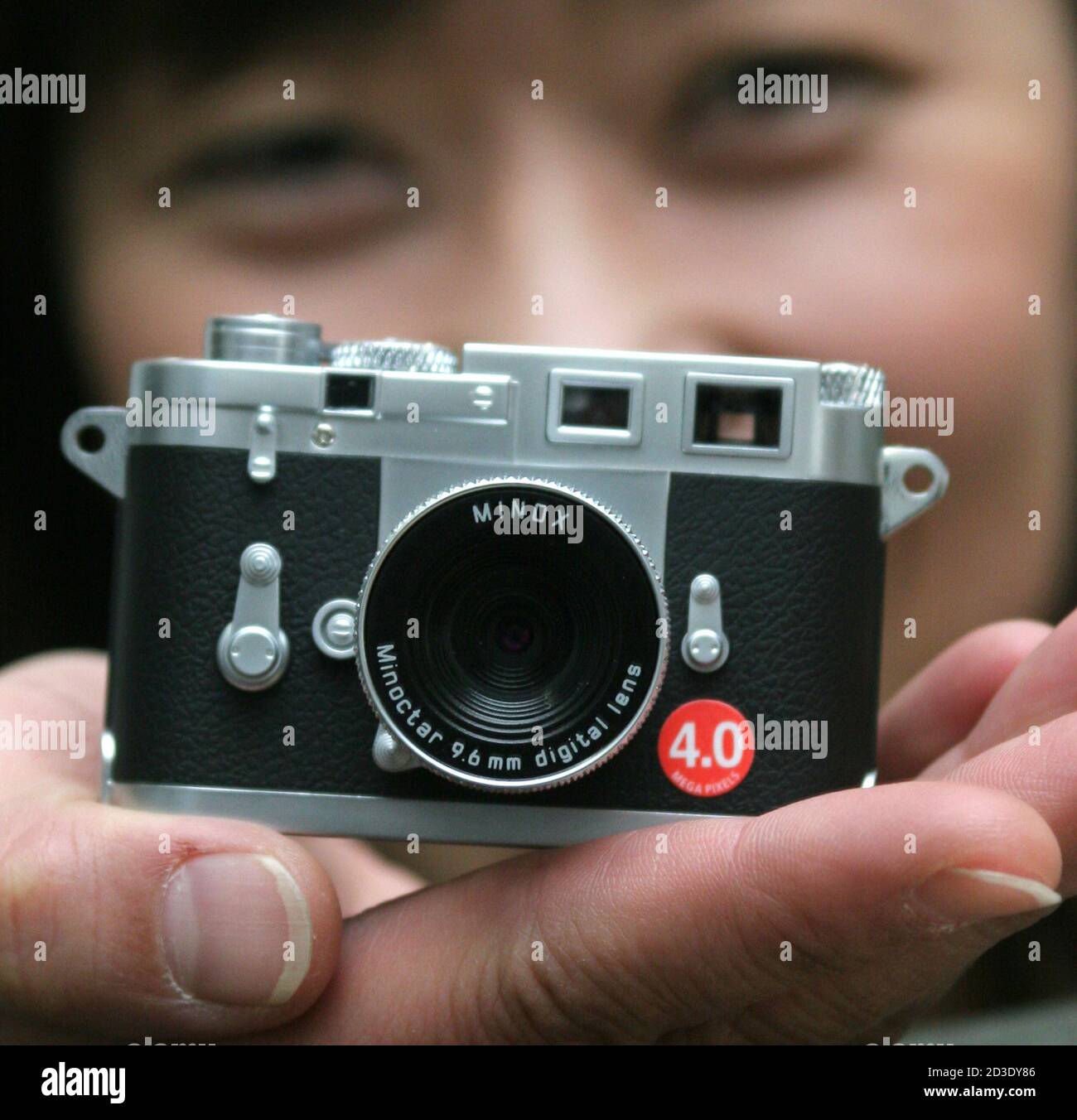 A Japanese woman shows the Minox miniature Leica M3 replica digital camera  in Tokyo February 23, 2005. Weighing only 95g (about 0.21lbs), the 4.0  megapixel digital camera can record up to 99