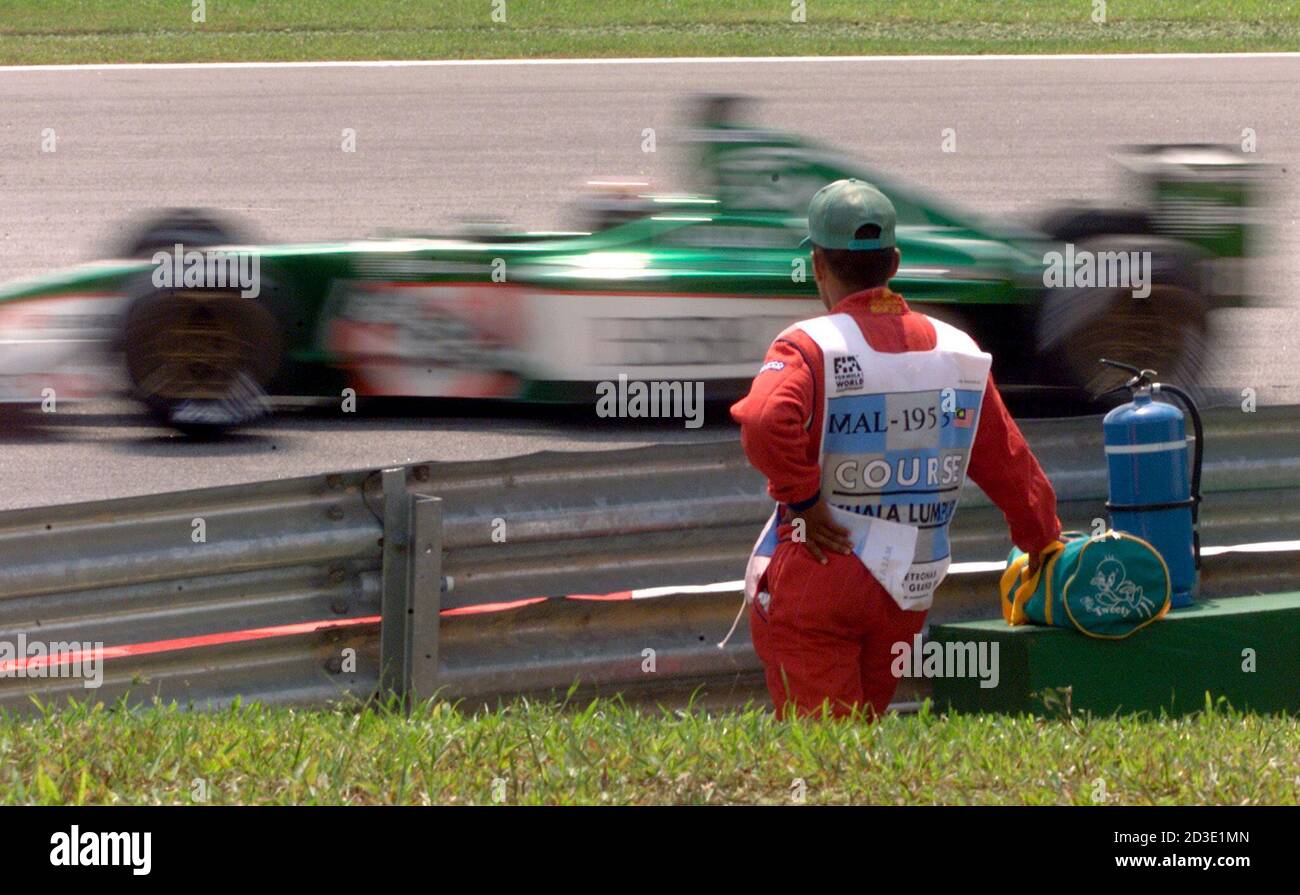 A TRACK MARSHALL KEEPS AN EYE ON A JAGUAR SPEEDING BY HIM DURING THE FIRST TIMED PRACTICE SESSION OF THE MALAYSIAN PRIX. A track marshall keeps an eye on Jaguar