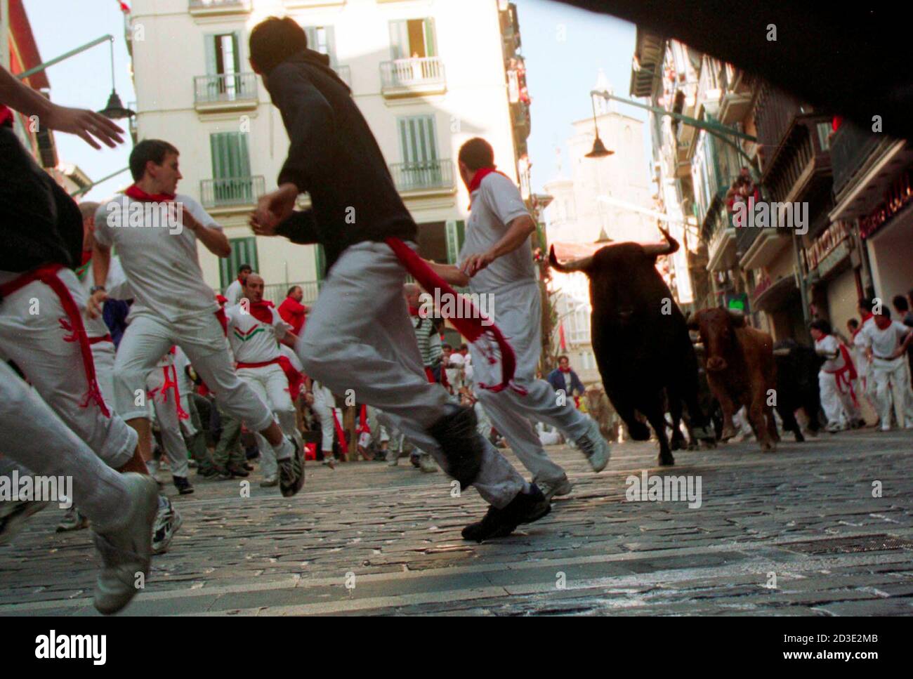 A group of runners lead a pack of fighting bulls from the Marques de Domecq ranch into a sharp corner turn in the 900-meter 'encierro', or running the bulls, through the old city streets of Pamplona, Spain during the July 12, 2001 morning event. Six fighting bulls stampede through the streets each morning in the week-long Fiesta de San Fermin which was brought to the world's attention in the mid-1920s by the American novelist Ernest Hemingway. The bulls are then fought and killed in a bullfight later the same day.  JWH Stock Photo