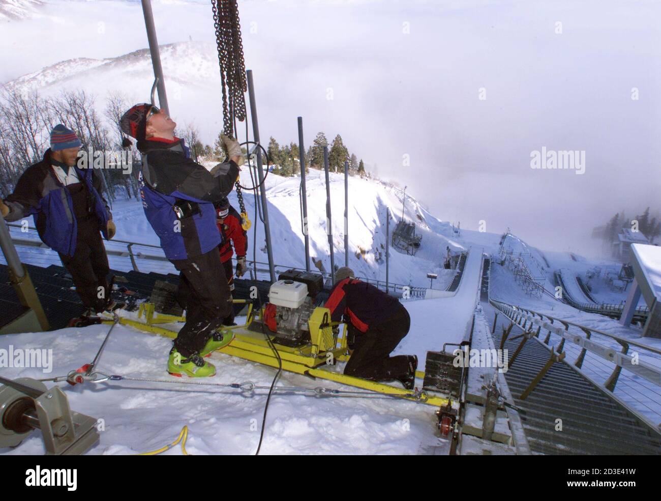 Garret Moe (C) and John Holmes (L) help install a motorized track layer at the top of the 120m ski jump at Utah Olympic Park, December 18, 2001. The motorized device lays ski tracks down the middle of the jump. The Olympic Park site will host ski jumping as well as all bobsleigh, luge and skeleton events from February 8-23, 2002. The XIX Olympic Winter Games are scheduled to run from February 8-24, 2002. REUTERS/Mike Blake  MB/HB Stock Photo