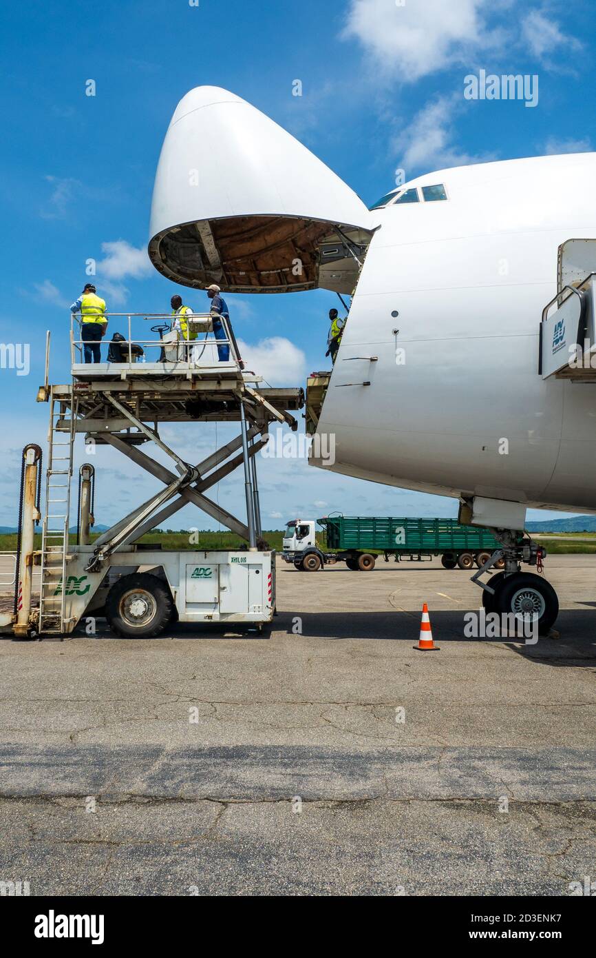 A Boeing B747 Jumbo Jet freighter aircraft with a wide open nose cargo door being offloaded by a