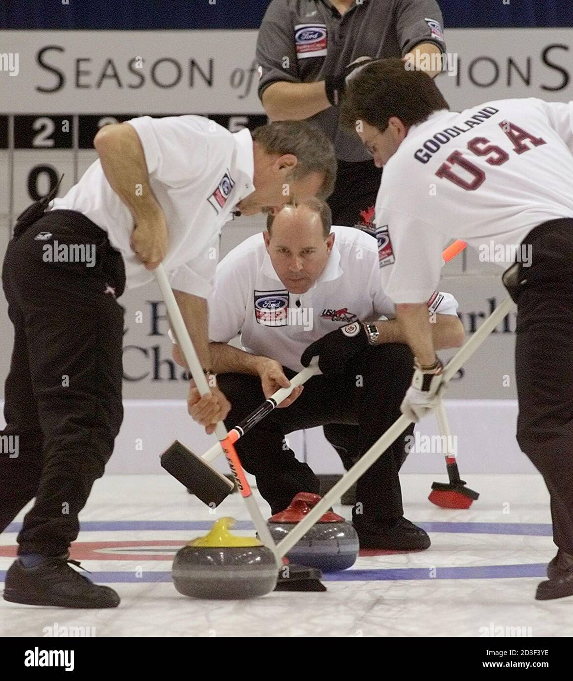 United States skip Paul Pustovar (C) watches the line of the rock as  teammates Mike Fraboni (L) and Geoff Goodland sweep hard during World  Curling Championship play against Canada in Bismarck, North