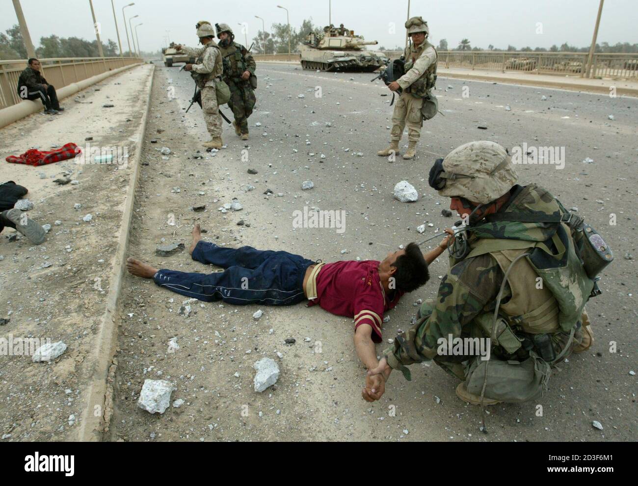 U.S. Marines from Lima Company, a part of a the 7th Marine Regiment, search men who they said were members of Iraqi Republican guard, dressed in civilian clothes for weapons on a bridge, in the suburbs of Baghdad on April 7, 2003. U.S. forces burst into the heart of Baghdad on Monday and entered two palace complexes of President Saddam Hussein, but they said the operation was an armoured raid not intended to hold territory.  REUTERS/Oleg Popov REUTERS Stock Photo