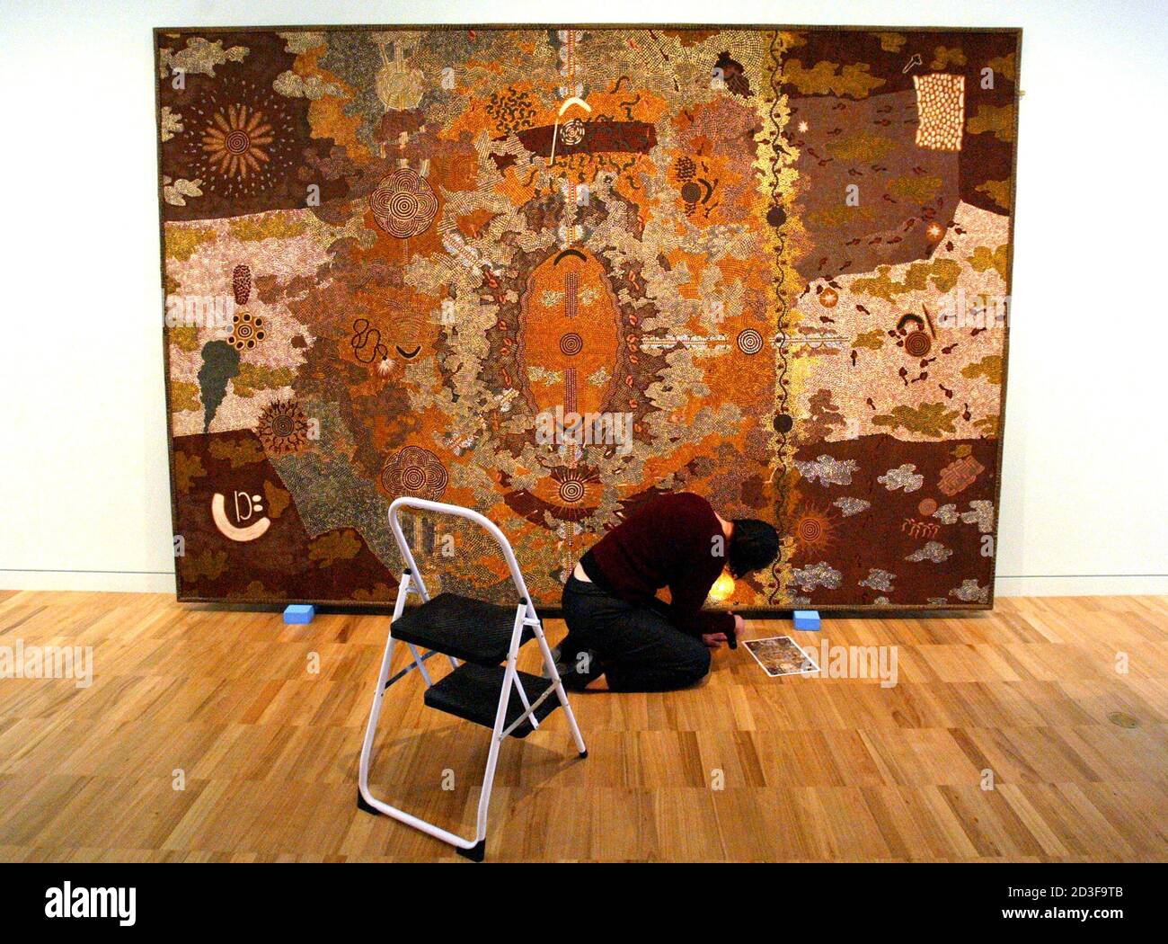 Painting Conservator Paula Dredge inspects one of the paintings to be