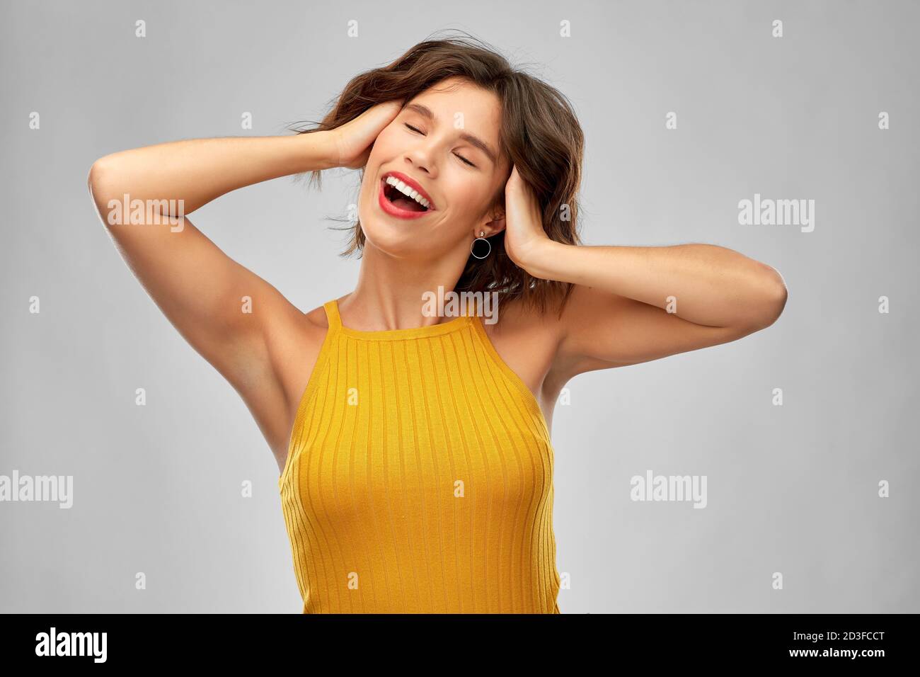 happy laughing young woman in mustard yellow top Stock Photo