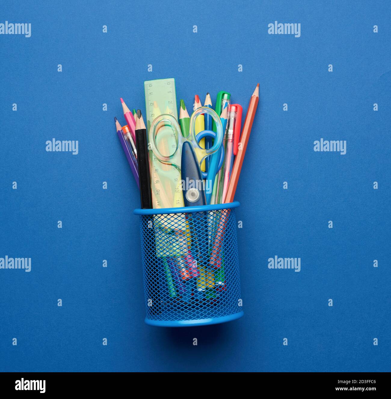 plastic scissors and multicolored wooden pencils on a blue background, flat lay, copy space Stock Photo