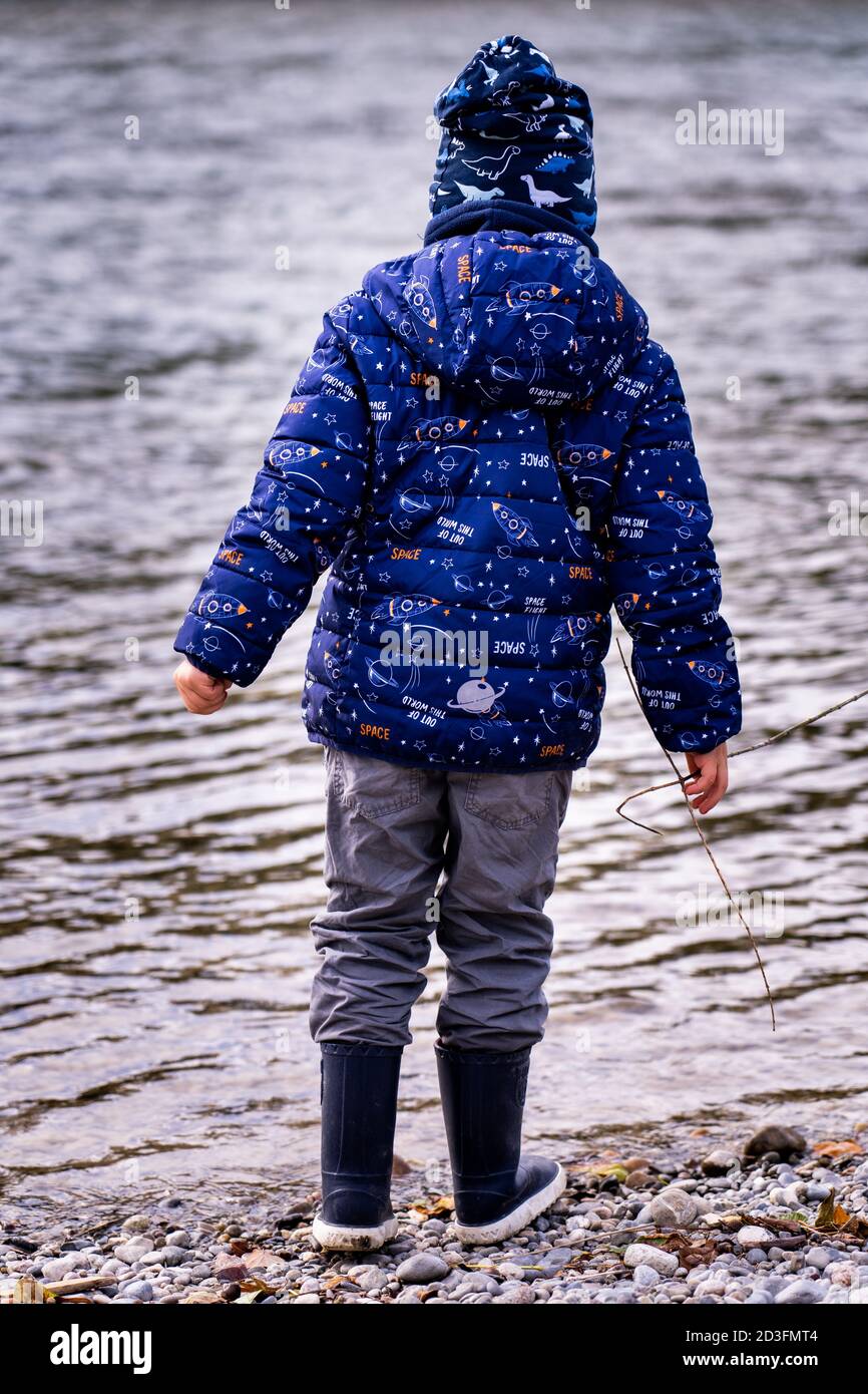 Boy standing at river bank winter day nature background. Happiness active lifestyle Stock Photo