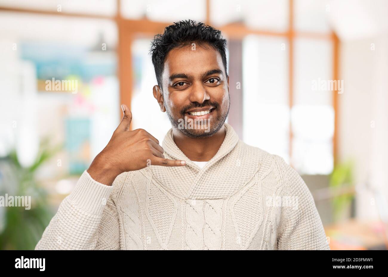 indian man in sweater making phone call gesture Stock Photo