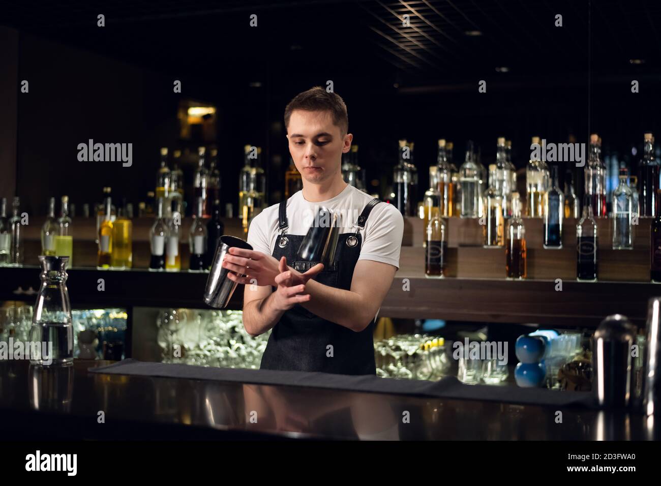 a young bartender hosts a show with shakers at the bar in a