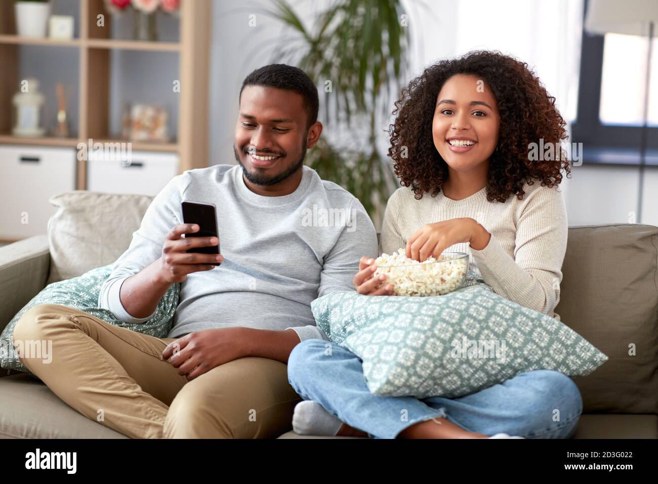 african couple with popcorn watching tv at home Stock Photo - Alamy