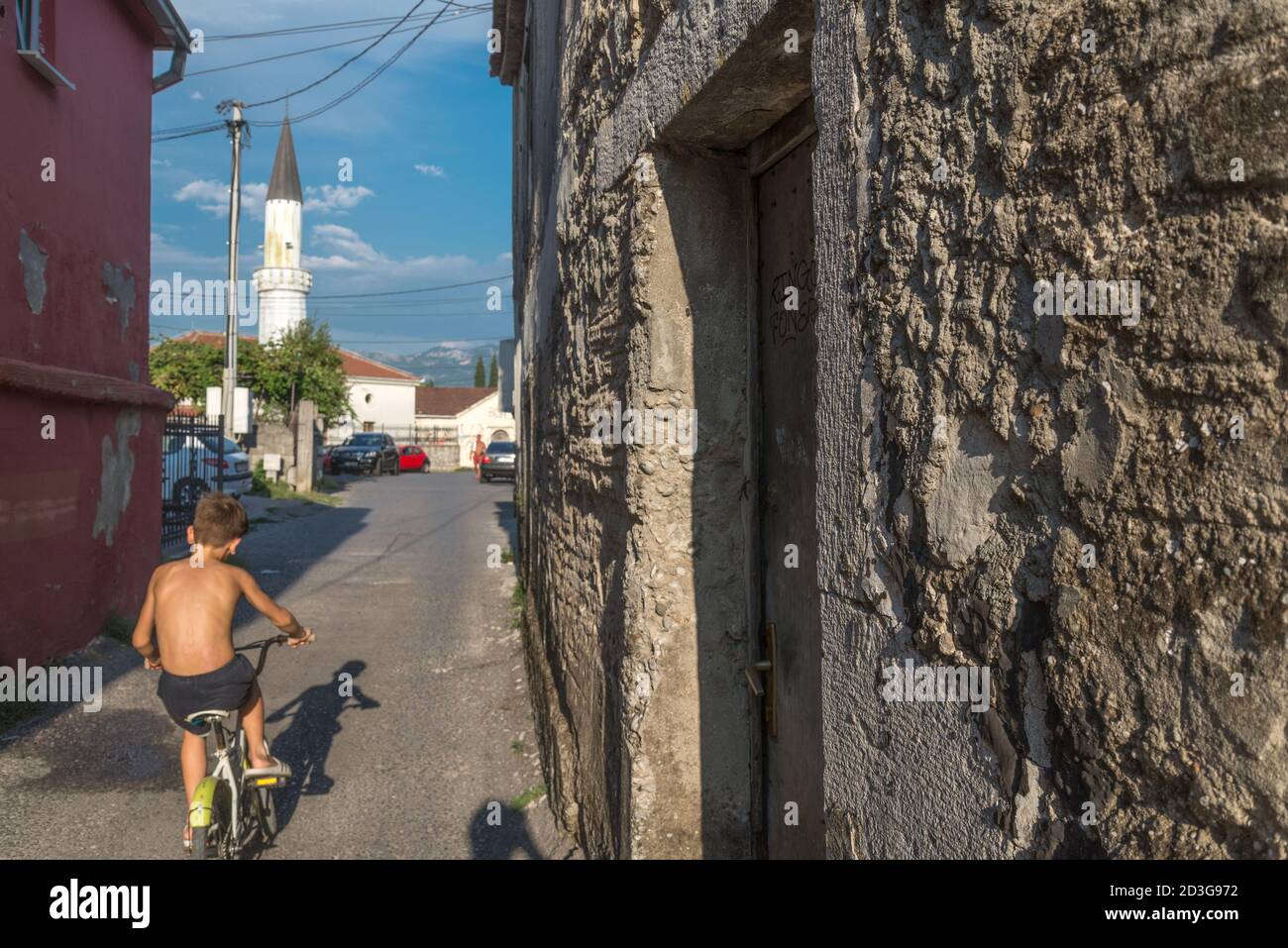 A young boy on a bicycle peddles his way through tne narrow stone streets of Stara Varas or the Old Town of Podgorica and toward one of it's Mosques. Stock Photo