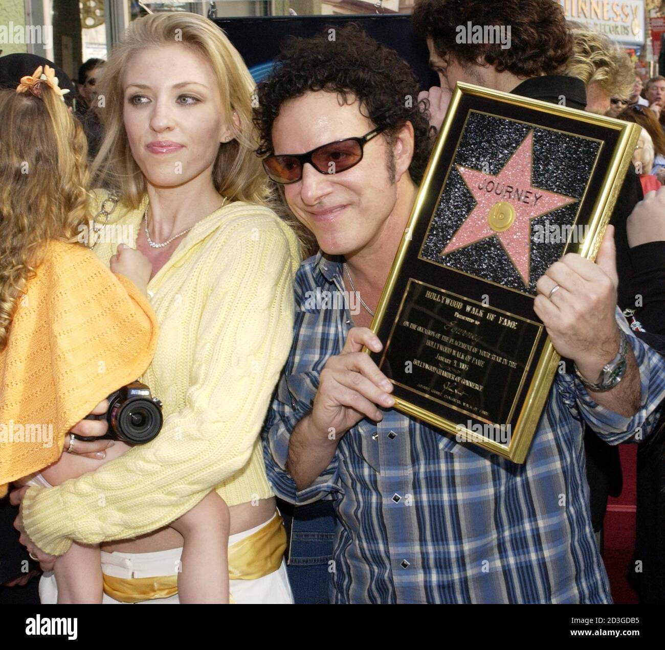 Neal Schon (R), of the rock band Journey, holds a replica plaque during an  unveiling ceremony honoring the group with the 2,275th star on the  Hollywood Walk of Fame January 21, 2005.