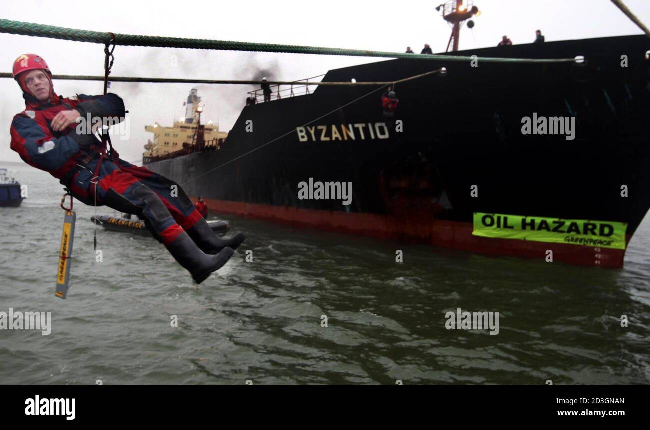 A member of the environmental organisation Greenpeace hangs in climbing gear near the oil tanker Bysantio in the port of Rotterdam December 4, 2002. The ageing oiltanker is under fire from environmentalists who claims it is posing an oil-spill threat following the disaster of the Prestige oil tanker which broke apart at sea off the Spanish coast two weeks ago. REUTERS/Jerry Lampen  JFL/JV Stock Photo